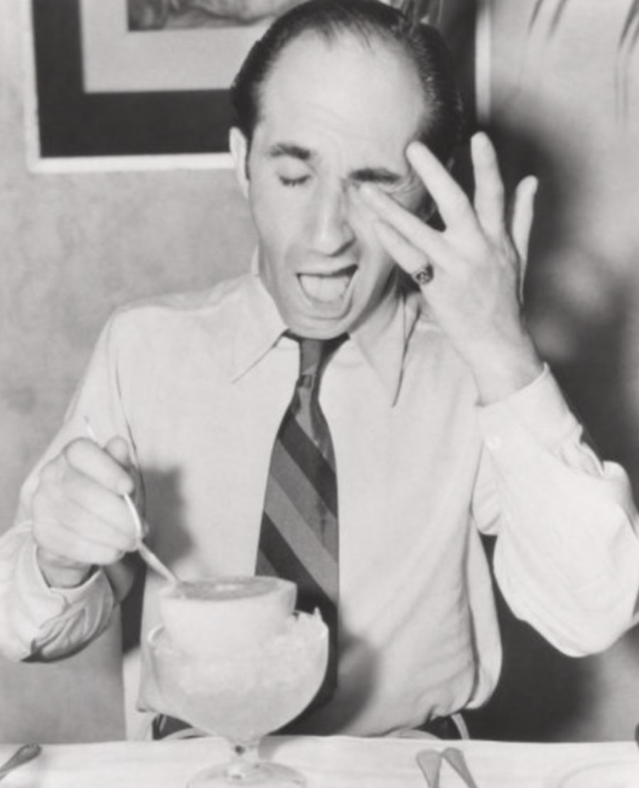 Photographie ancienne en noir et blanc illustrant la gêne oculaire allergique — frottement des yeux pendant un repas