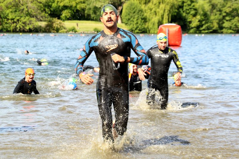 Dr Alexandre Hage exiting the water after an open-water swim, in a triathlon wetsuit
